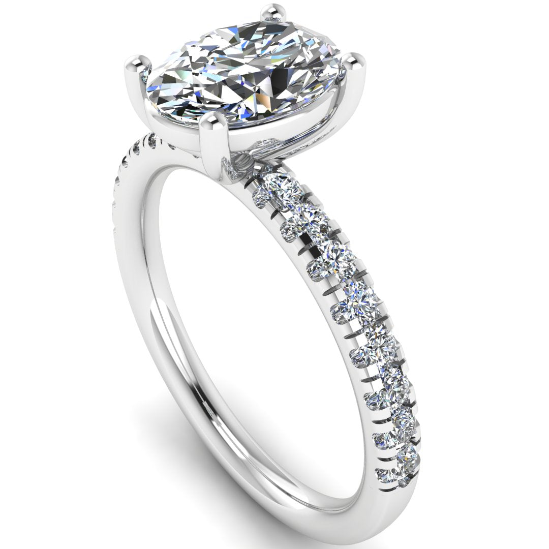 Angled view of white gold and platinum engagement ring with oval cut lab grown diamond set on a pave band with side shoulder stones