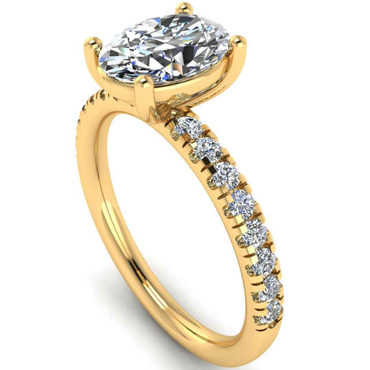 Angled view of yellow gold engagement ring with oval cut lab grown diamond set on a pave band with side shoulder stones