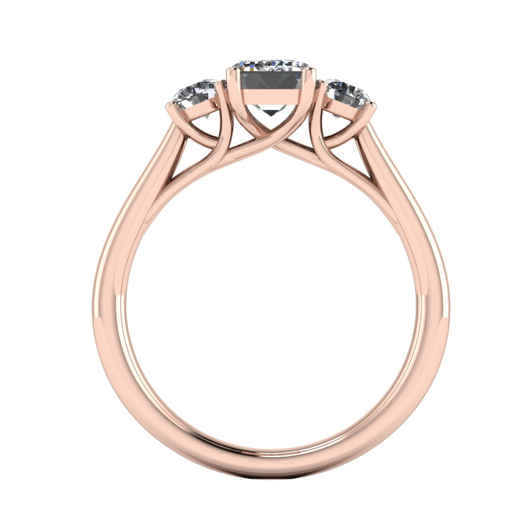 flat view of a trilogy rose gold engagement ring set with an emerald centre lab grown diamond with two round brilliant diamonds on either side of the centre stone