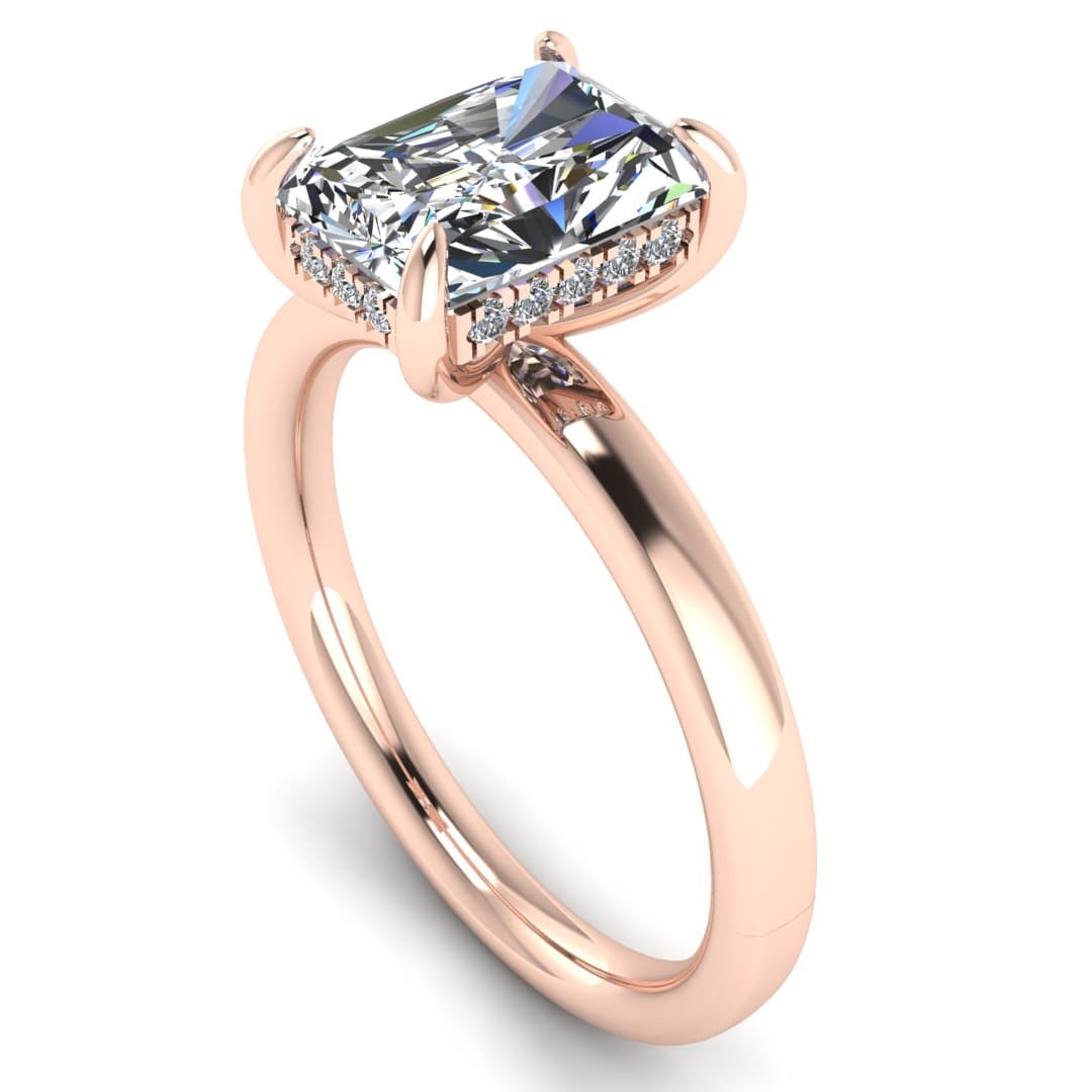 angled view of a rose gold single solitaire engagement with set with a radiant cut lab grown diamond featuring a secret hidden under halo