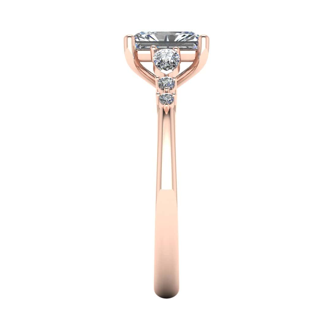 side view of a rose gold multi-stone lab grown diamond engagement ring. It features a radiant cut lab-grown diamond with one pear and two round side diamonds on either side