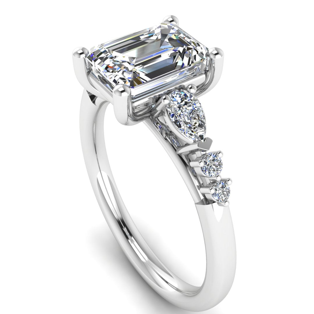 angled view of a platinum and white gold engagement ring. There is an emerald cut centre lab grown diamond with an arrangement of pear shaped and round diamonds on each side