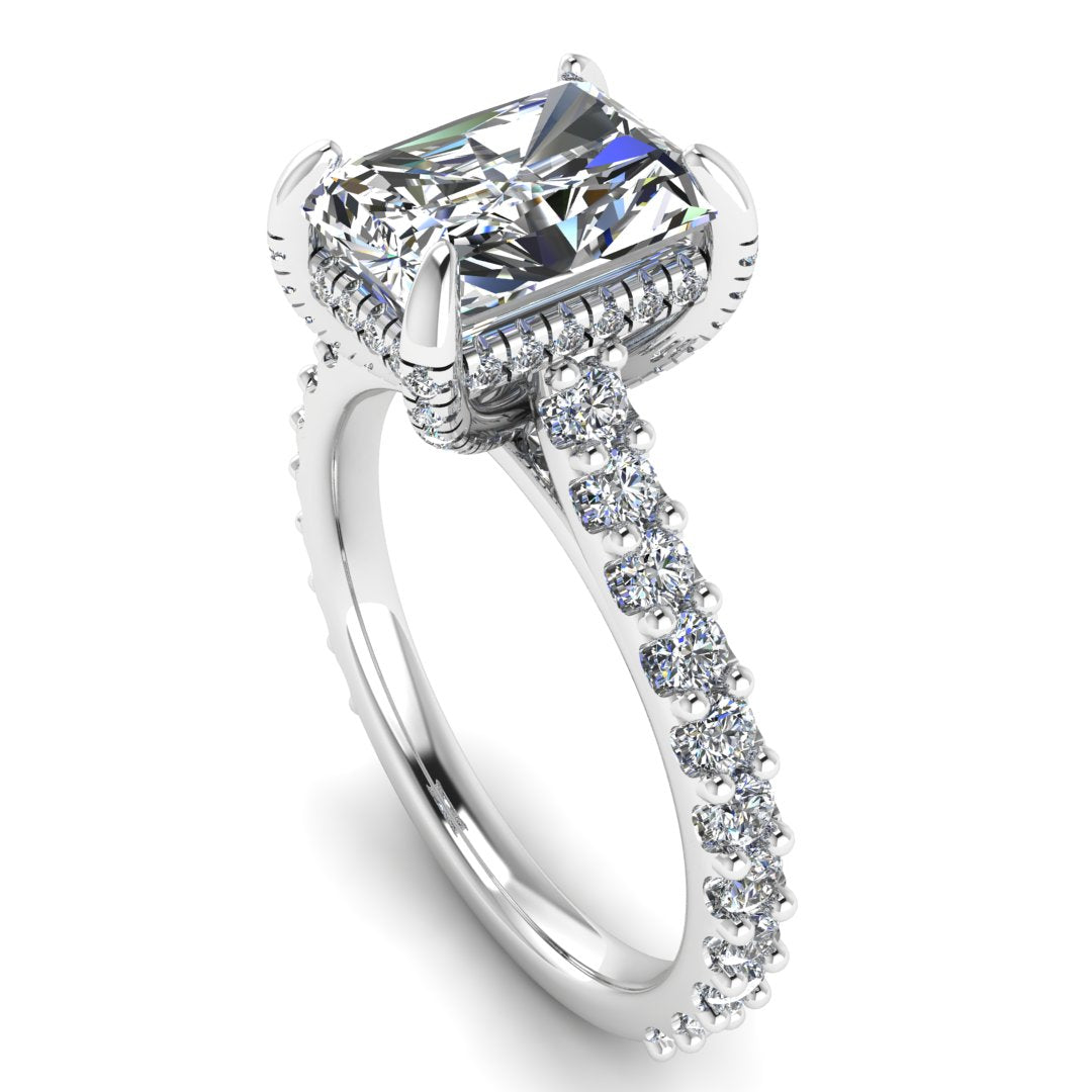 angled view of Ellie platinum or white gold engagement ring which has a central emerald cut lab grown diamond, elegant under-halo, pavé-set shoulders, and delicate diamonds on the prongs for extra sparkle