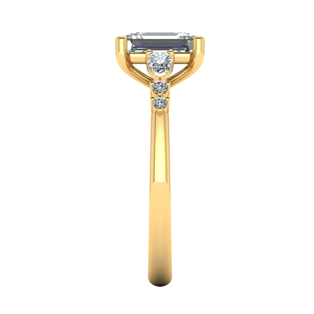side view of yellow gold engagement ring. There is a emerald cut centre lab grown diamond with an arrangement of pear shaped and round diamonds on each side