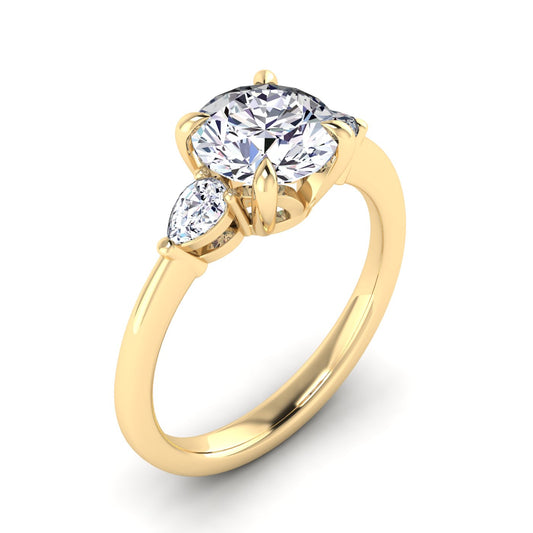 Angled view of a yellow gold trilogy engagement ring using round and pear shaped lab grown diamonds