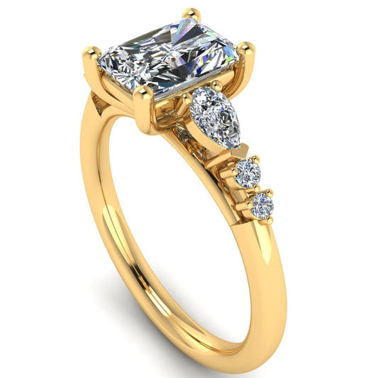 angled view of a yellow gold multi-stone lab grown diamond engagement ring. It features a radiant cut lab-grown diamond with one pear and two round side diamonds on either side