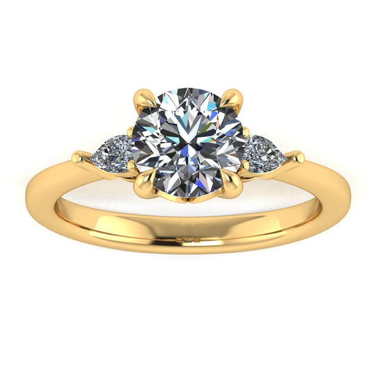 Front view of a yellow gold trilogy engagement ring using round and pear shaped lab grown diamonds